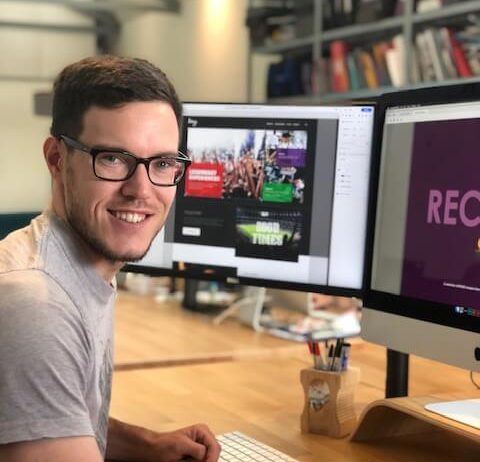 Ryan is sat at his desk and turned towards the camera smiling