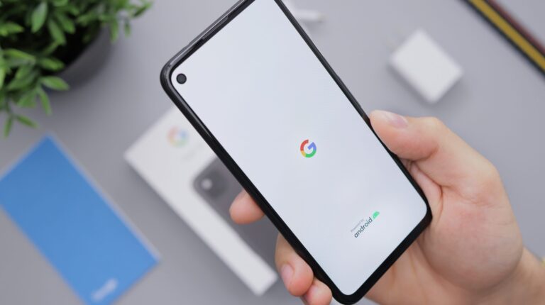 A hand holding a phone with the Google logo in the centre of the screen