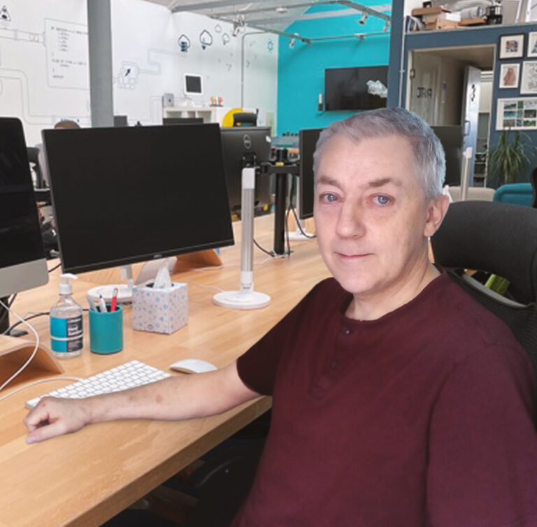 A picture of our developer Amos sat at his desk in the Fanatic office with his face turned towards the camera